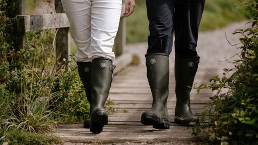 Focused on wellington boots walking across a bridge